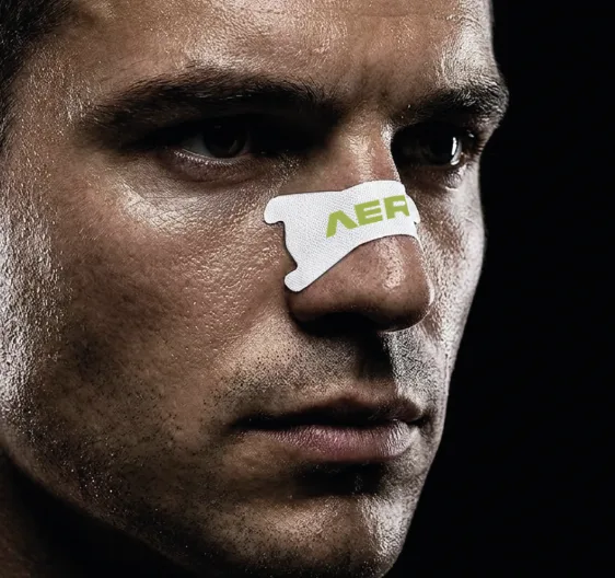 Close-up of an athlete's face wearing a white AERO2 nasal strip, moody low-key lighting