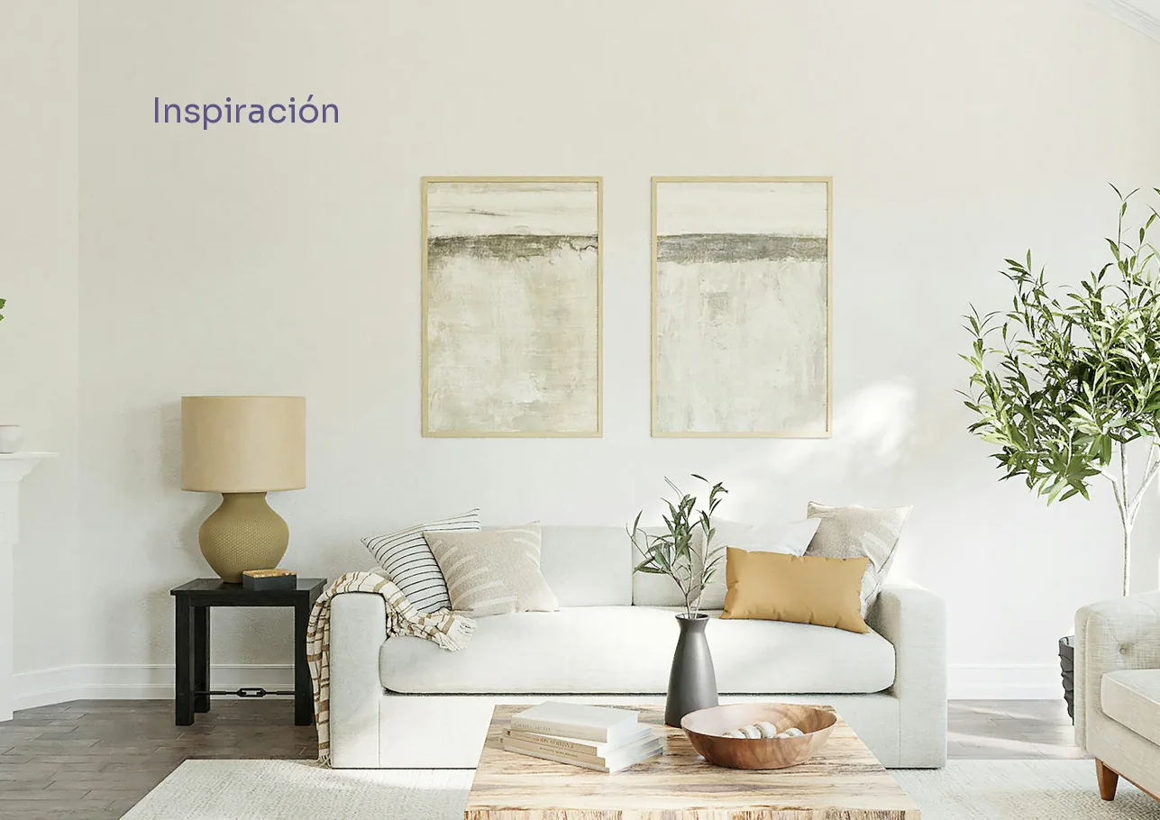 Inspiration opener: a cream sofa with striped cushions under two framed artworks, a table lamp and an olive tree in a calm beige living room