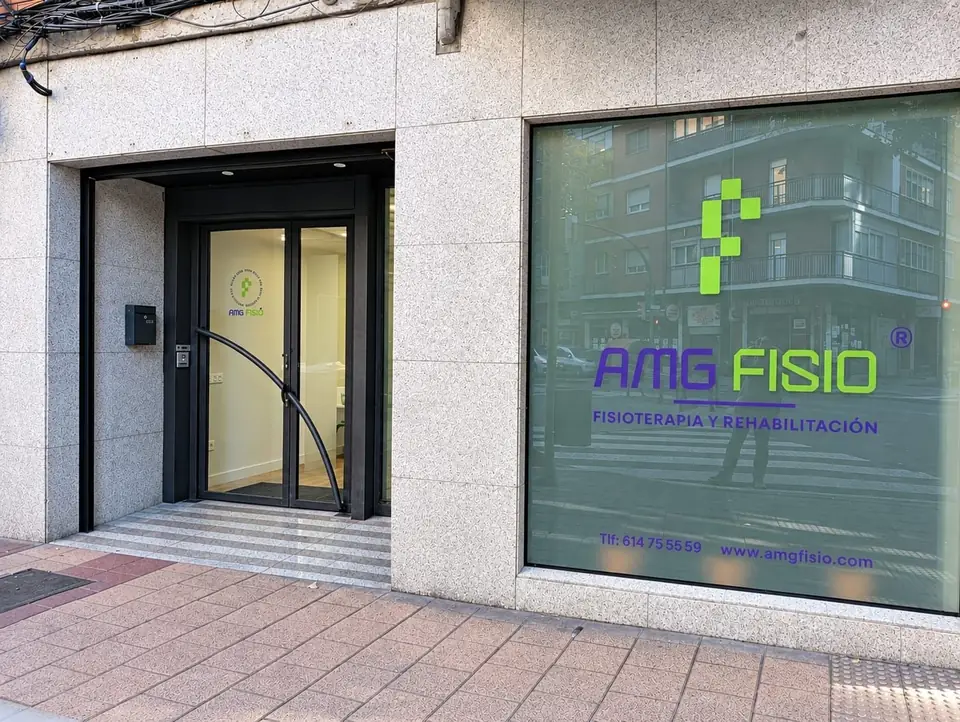 AMG Fisio storefront on Calle Huelgas 8, Valladolid: green isotype and purple wordmark on the tinted window film