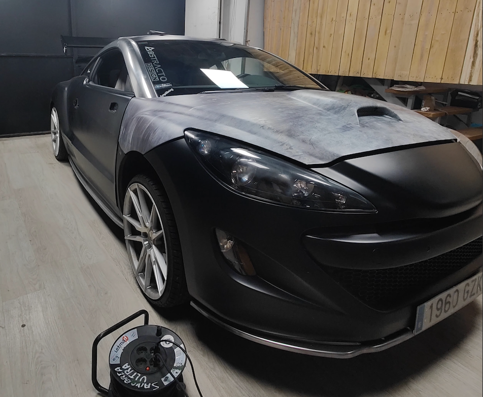 Peugeot RCZ mid-installation with radioactive wrap partially applied, showing progress across body panels