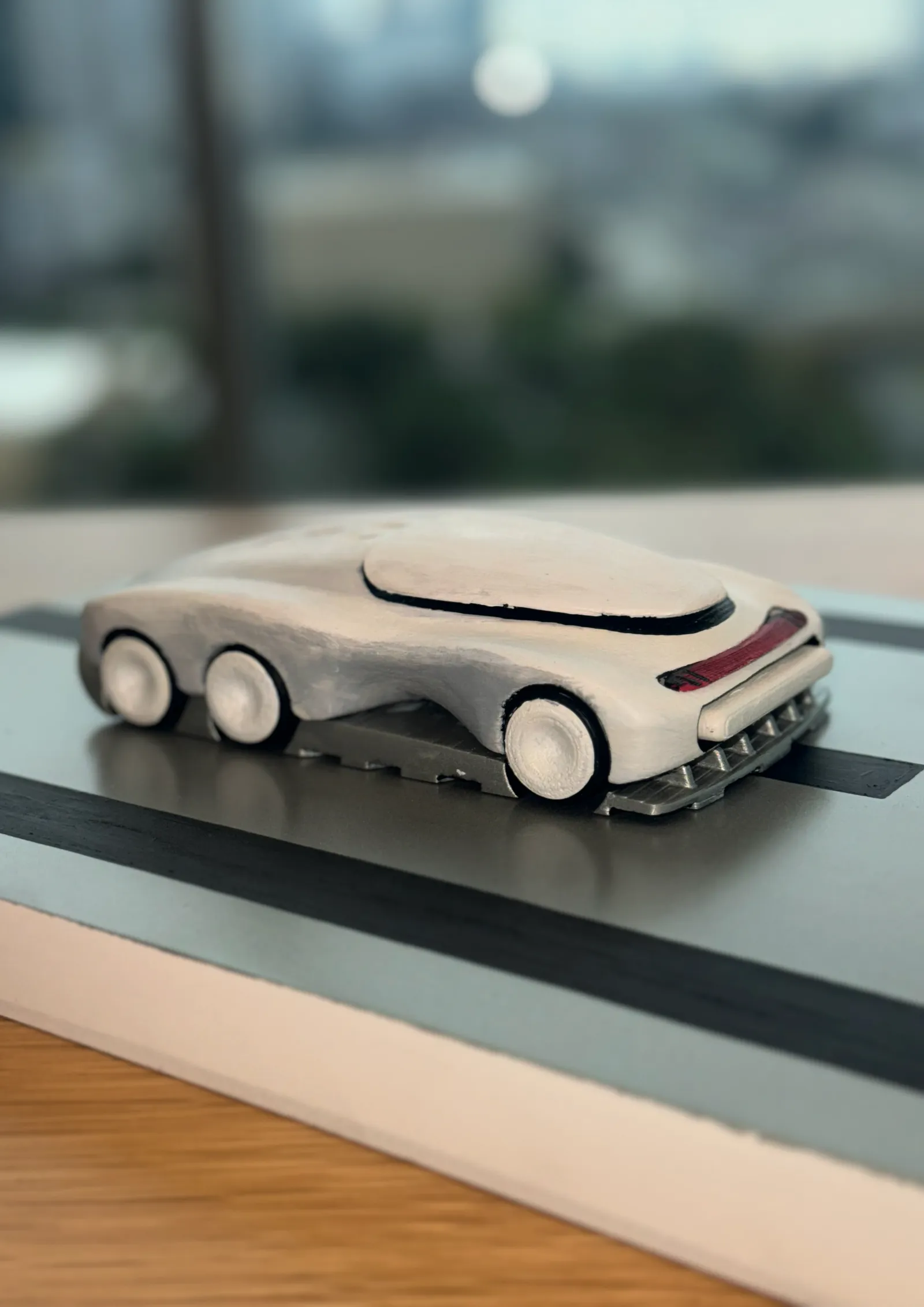 Low side view of the printed car showing three axles of wheels on the road plate