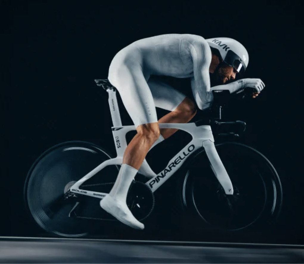 Progressives persona reference: a cyclist in a full white aerodynamic skinsuit and aero helmet, tucked low over a time-trial bike