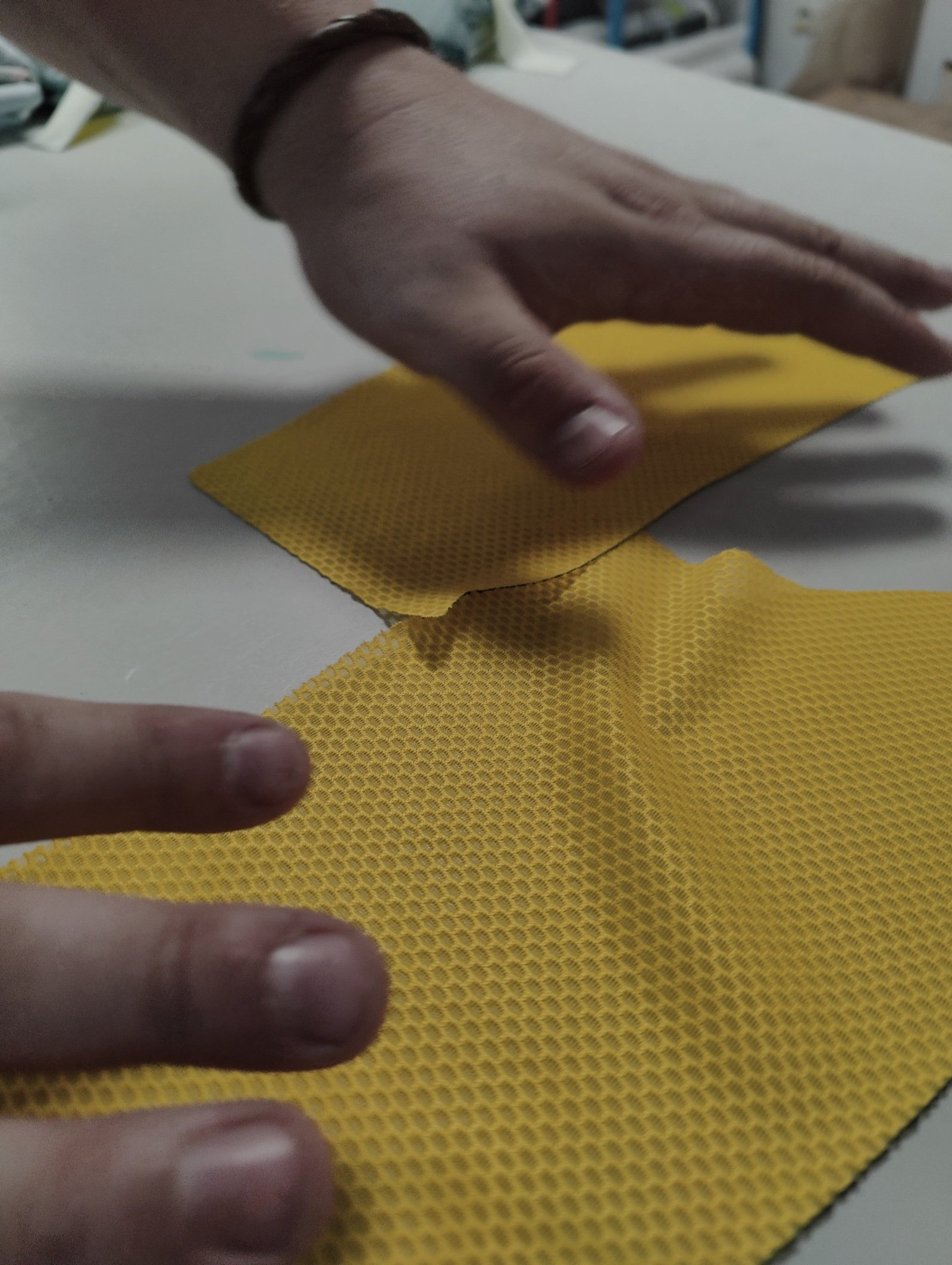 Hands checking the edge and structure of a laser-cut honeycomb technical fabric panel